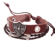 Detail of multi-layer leather bracelet with vintage metal shield charm and tassels