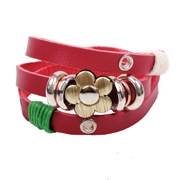 Macro shot of red leather wrap bracelet featuring a retro gold floral metal charm