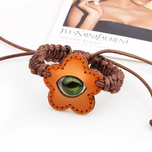Ethnic woven bracelet featuring a leather flower charm and luminous evil eye bead