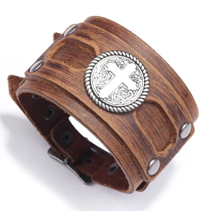 Detail of vintage brown leather cuff bracelet featuring embossed cross medallion and studs