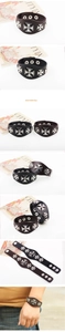 Detail of punk leather bracelet featuring metal iron cross studs and snap button closure