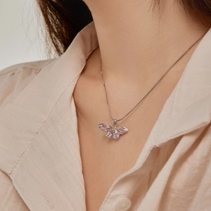 Macro detail of silver butterfly pendant with colorful zircon stones on snake chain