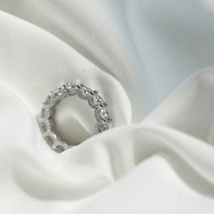 Gros plan d'une bague éternité en argent S925 sertie de pierres sur de la soie blanche