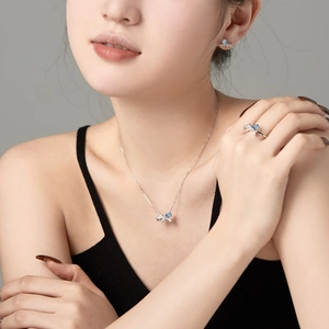 Detailansicht eines silbernen Schleifen-Schmucksets mit blauen Zirkonia am Modell
