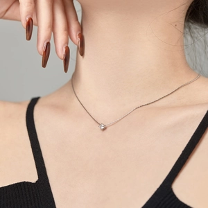 Close-up of minimalist S925 silver necklace with a sparkling round zircon pendant on neck