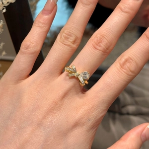 Elegante anello a fiocco dorato con pietra a goccia e pavé sulla mano di un modello