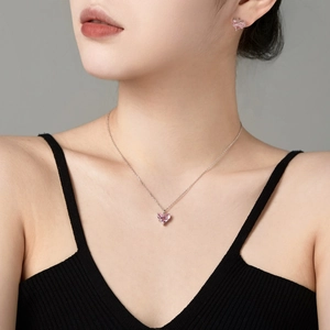 Detailed close-up of pink heart zircon pendant necklace and stud earrings on model