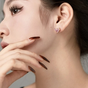 Nahaufnahme eines herzförmigen rosa Edelstein-Ohrrings am Ohr des Models