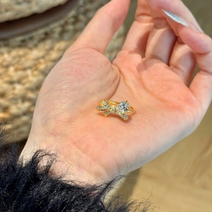 Dettaglio di un anello a fiocco dorato con diamanti e una pietra a goccia centrale