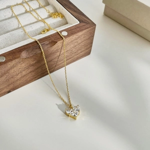 Detail of gold necklace featuring two heart-shaped zircon stones in a claw setting