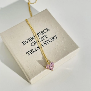 Detailed close-up of a pink heart-shaped zircon necklace in a gold jewelry gift box