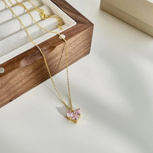 Detailed macro view of a heart-shaped pink zircon pendant on a delicate gold-plated chain