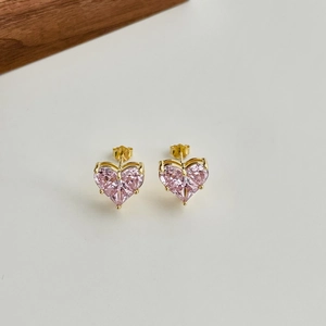 Nahaufnahme von herzförmigen S925 Silbersteckern mit rosa Zirkonia und Goldfassungen