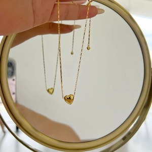 Detail of a gold heart pendant necklace on a box chain with mirror reflection effect