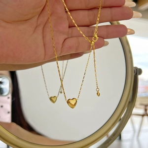 Macro detail of a gold heart pendant necklace with high-polish finish and adjustable chain