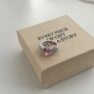 Macro view of heart-shaped pink diamond ring with sparkling side stones on a gift box