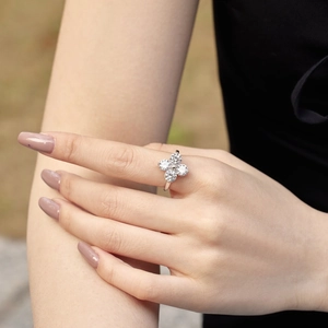 Macro shot of silver clover ring with four round zircon stones on female finger
