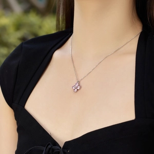 Detail shot of a silver four-leaf clover necklace with pink teardrop zirconia stones