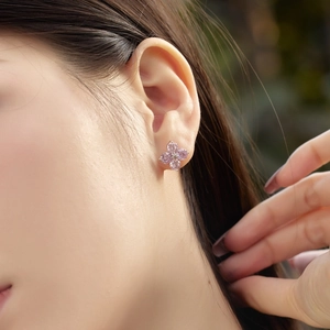 Close-up of pink clover flower stud earrings with nano zircon on a model in nature