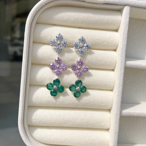 Macro shot of silver flower earrings with white, pink, and green zircon in a velvet box