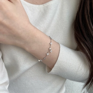 Detail of S925 sterling silver bracelet with clover charms and cubic zirconia on wrist