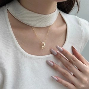 Detail of gold crescent moon pendant with micro-inlaid zircons and star tassels