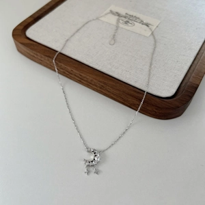 Detail of moon pendant with zircon inlay and star tassels on a silver snake chain
