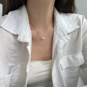 Close-up of minimalist gold necklace with three sparkling white zircon stones on a model