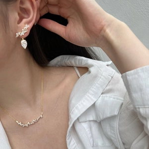 Close-up of a model wearing a gold smile necklace and teardrop earrings with zircons