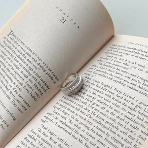 Close-up of S925 sterling silver multi-layer ring with sparkling zircon in a book
