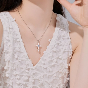 Close-up of a S925 sterling silver cross necklace with white opal and blue stone on a model