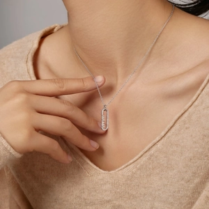 Détail du collier pendentif MAMA en argent S925 porté par un mannequin sur un pull beige