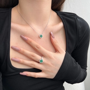 Détail macro du collier et de la bague trèfle en argent S925 avec zircons verts