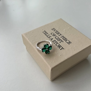 Detailed close-up of S925 silver ring featuring a green heart zircon clover on a gift box