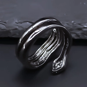 Macro shot of a tiered silver snake ring with detailed engraving on dark textured rock