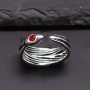 Macro detail of silver vintage snake ring featuring scales and red gemstone eyes