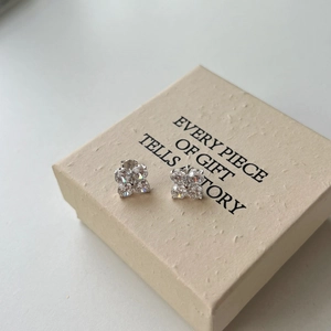Detailed view of silver clover stud earrings with cubic zirconia in a gift box