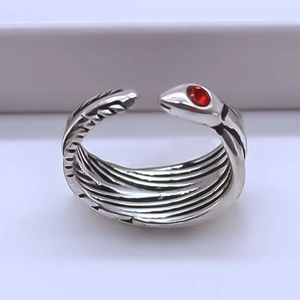 Macro detail of vintage snake ring with textured silver band and red gemstone eye
