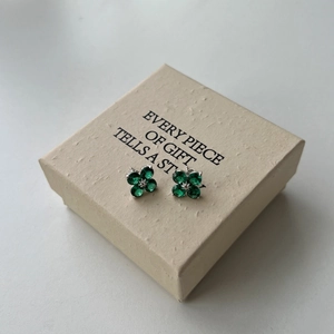 Detail of silver clover earrings with green gemstones inside an elegant gift box