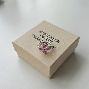 Vue détaillée de la bague trèfle en argent avec zircons roses sur un coffret cadeau