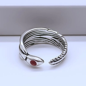 Macro detail of vintage silver snake ring featuring scales and a red gemstone eye