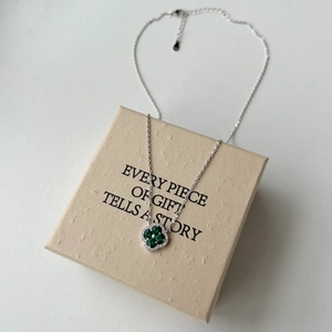 Vue détaillée d'un pendentif trèfle à quatre feuilles en argent avec pierre verte et zircons