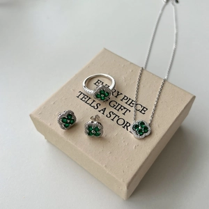 Détail d'un ensemble de bijoux trèfle à quatre feuilles argenté avec pierres vertes