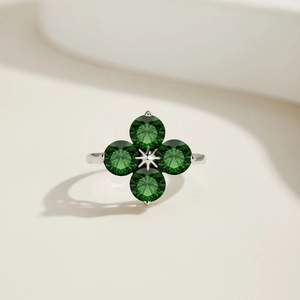 Détail macro d'une bague trèfle en argent avec des zircons verts de coupe ronde