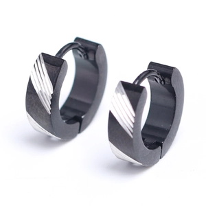 Dettaglio macro degli orecchini in acciaio nero con motivi a strisce diagonali argento