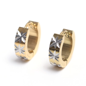Detail of gold huggie hoop earrings featuring engraved silver starburst patterns