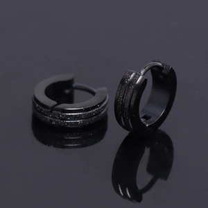 Detail of matte black men's hoop earrings with parallel glitter bands and reflections