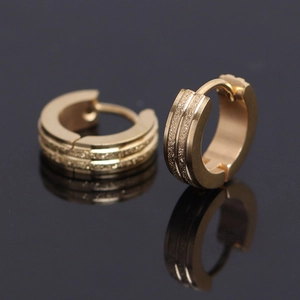 Macro detail of gold triple-layer huggie earrings with textured and polished finish
