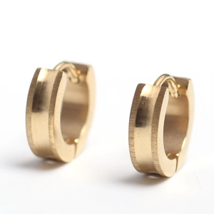 Close-up of golden stainless steel huggie earrings with a brushed matte texture finish