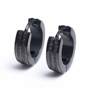 Close-up of black stainless steel huggie earrings with a textured matte sandblast finish